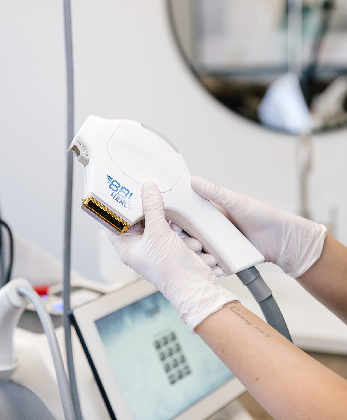 Hand holding a BBL HEROic laser in a treatment setting.