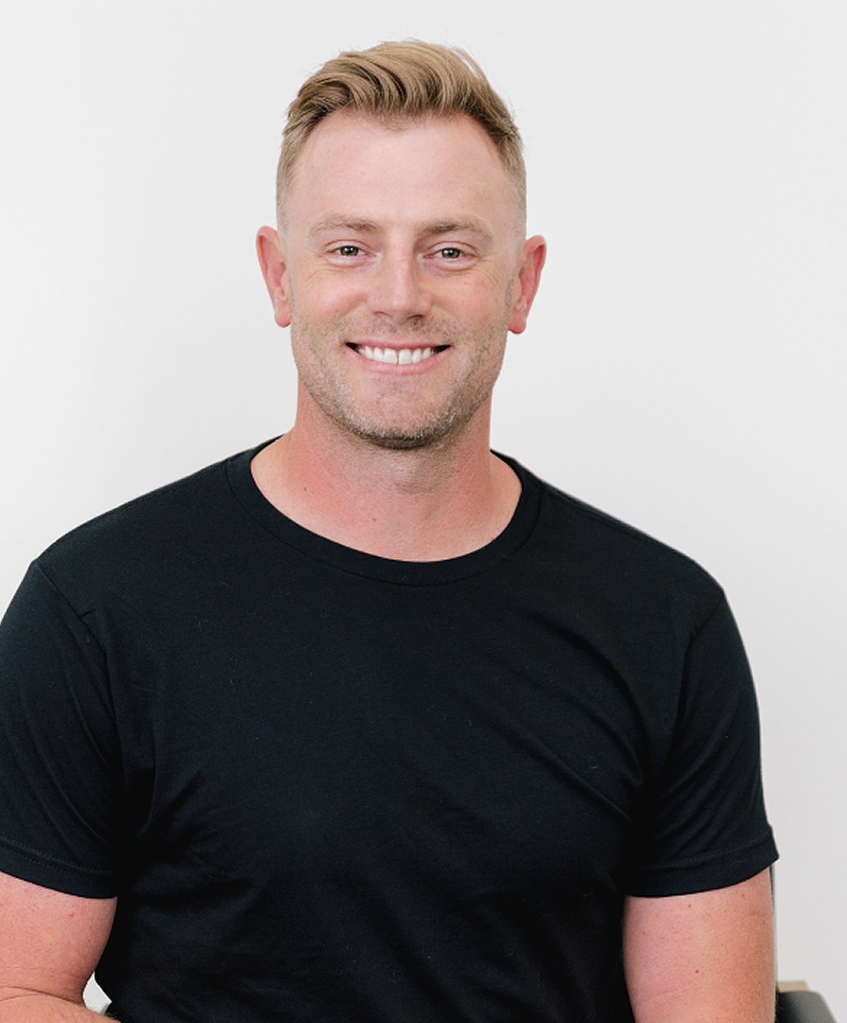 Smiling man in black t-shirt against white background.