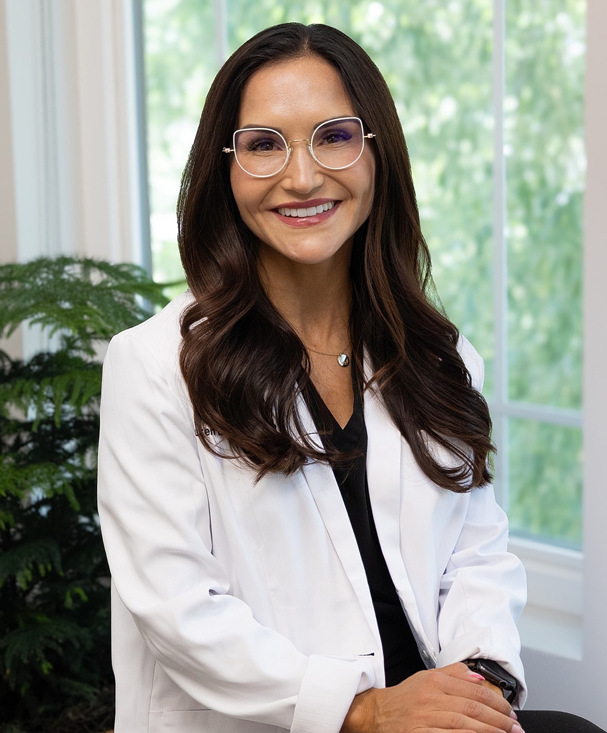 Smiling woman in a white coat indoors.