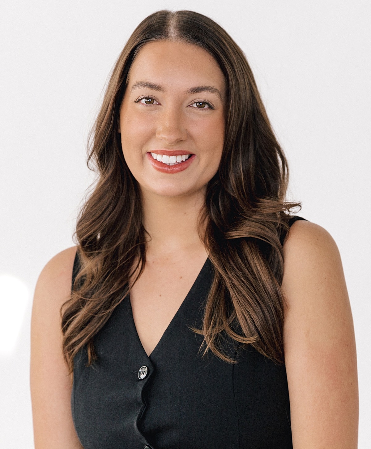 Smiling woman in a black outfit against white background.