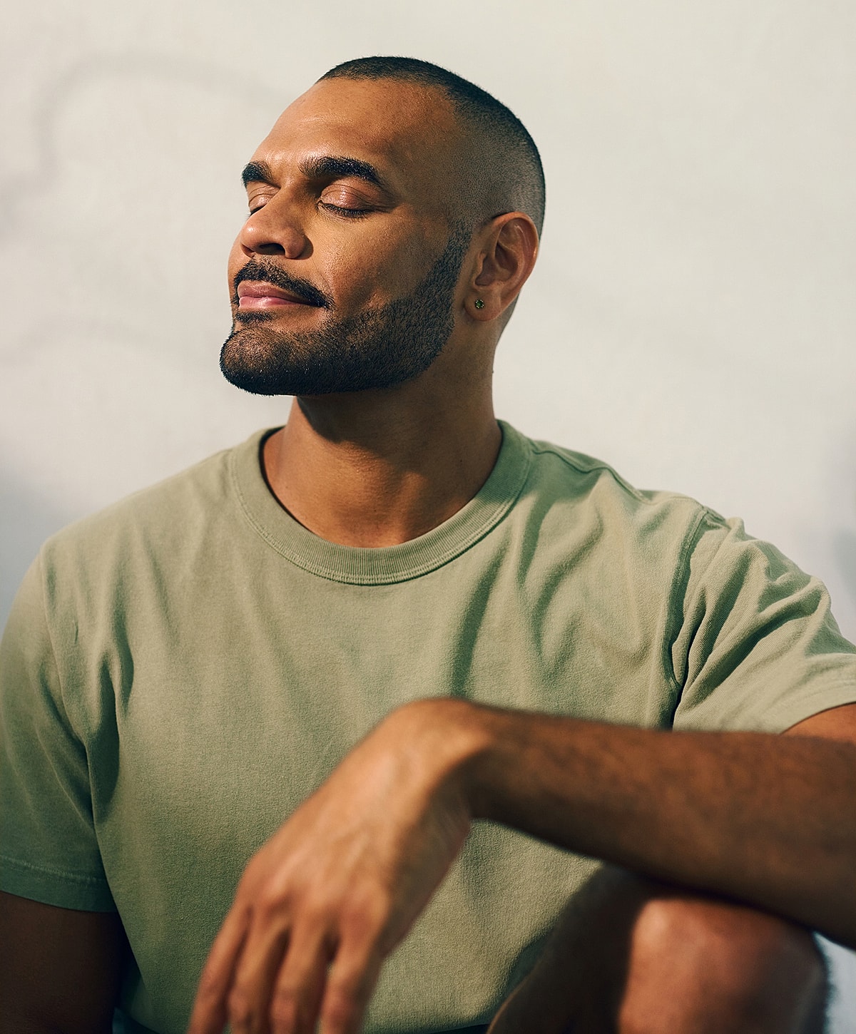 Man with closed eyes, relaxed expression, wearing green shirt.