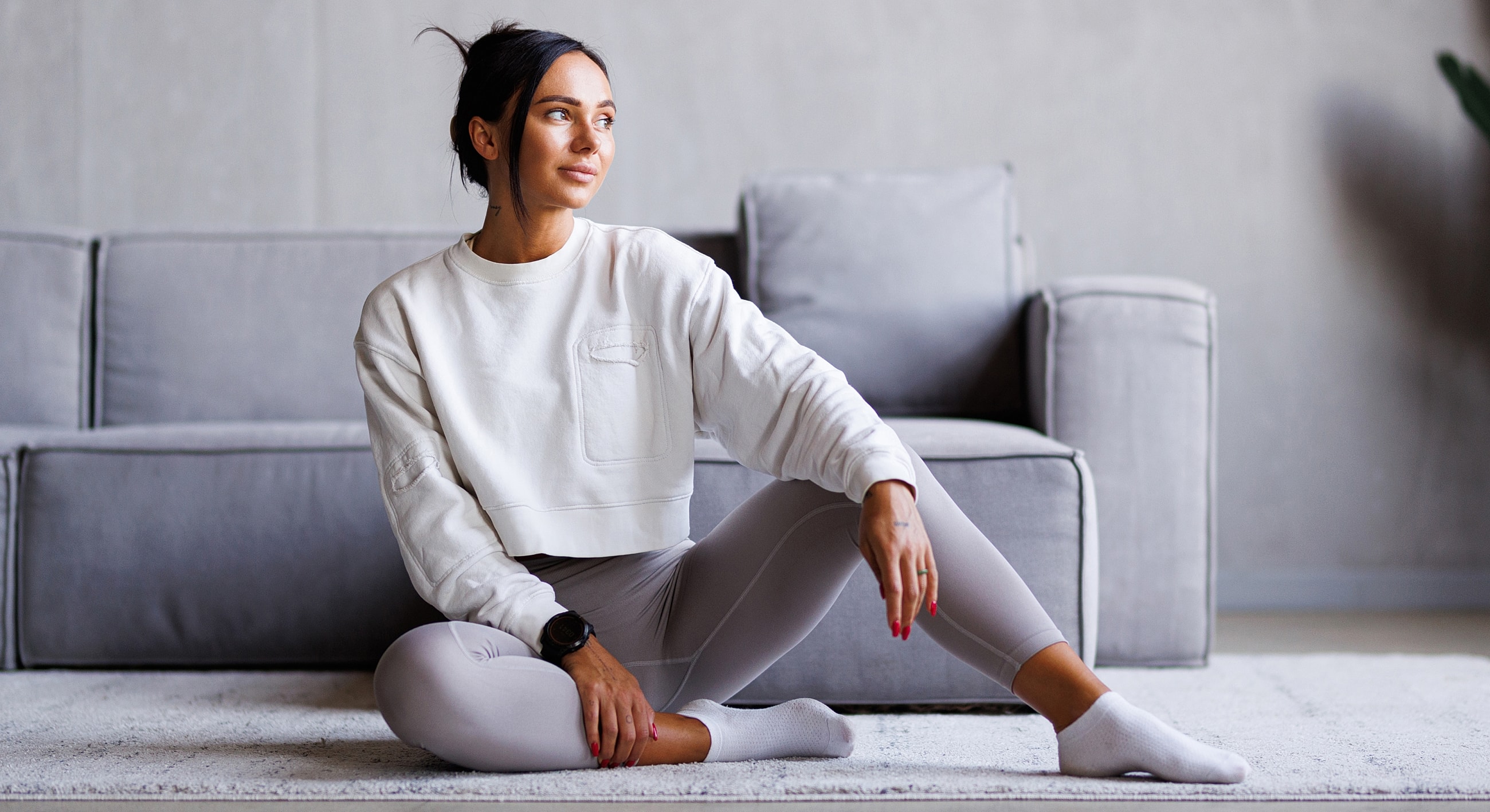 Woman in workout attire, sitting on a rug.
