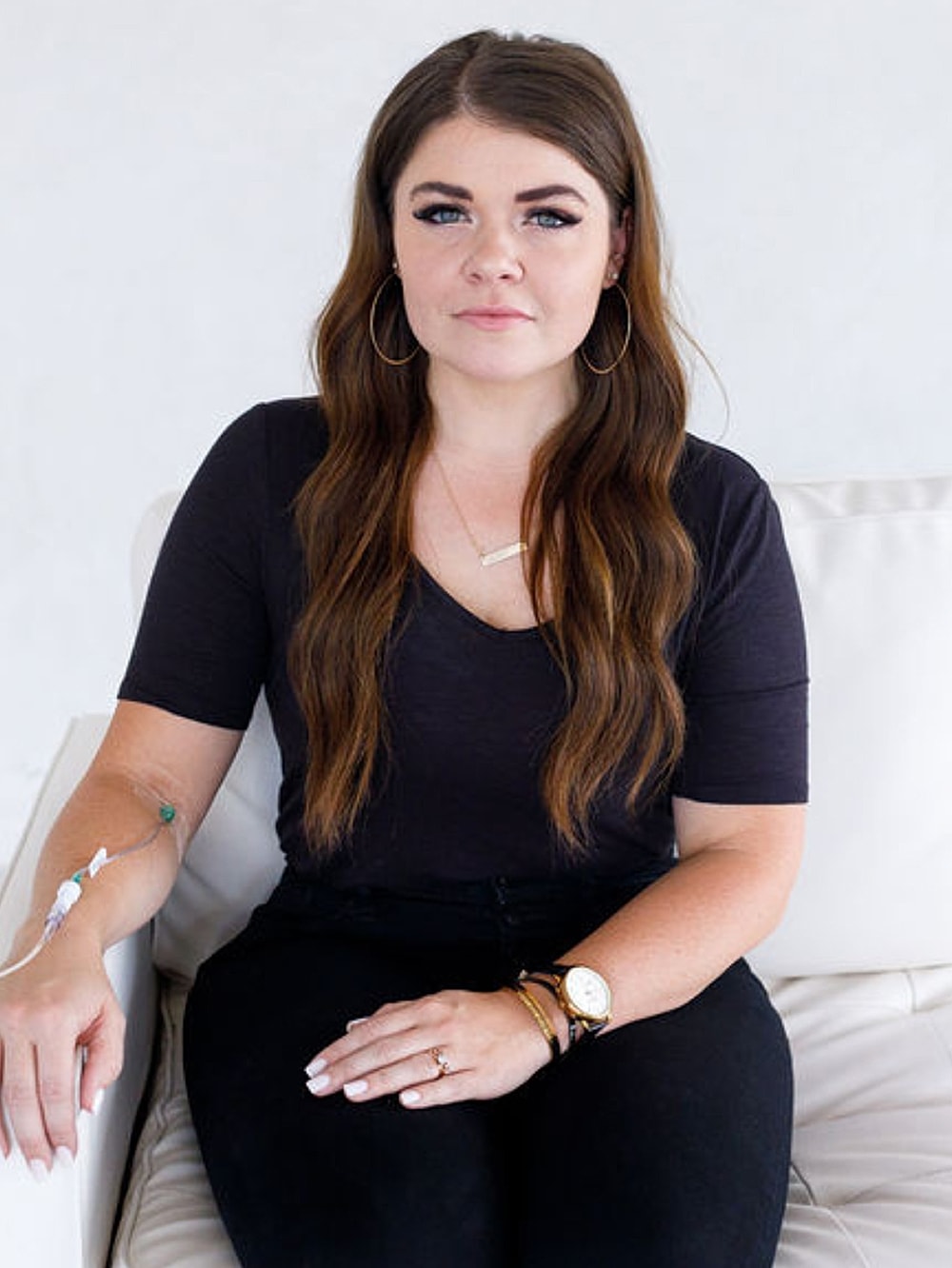 Woman sitting with medical IV line in arm.